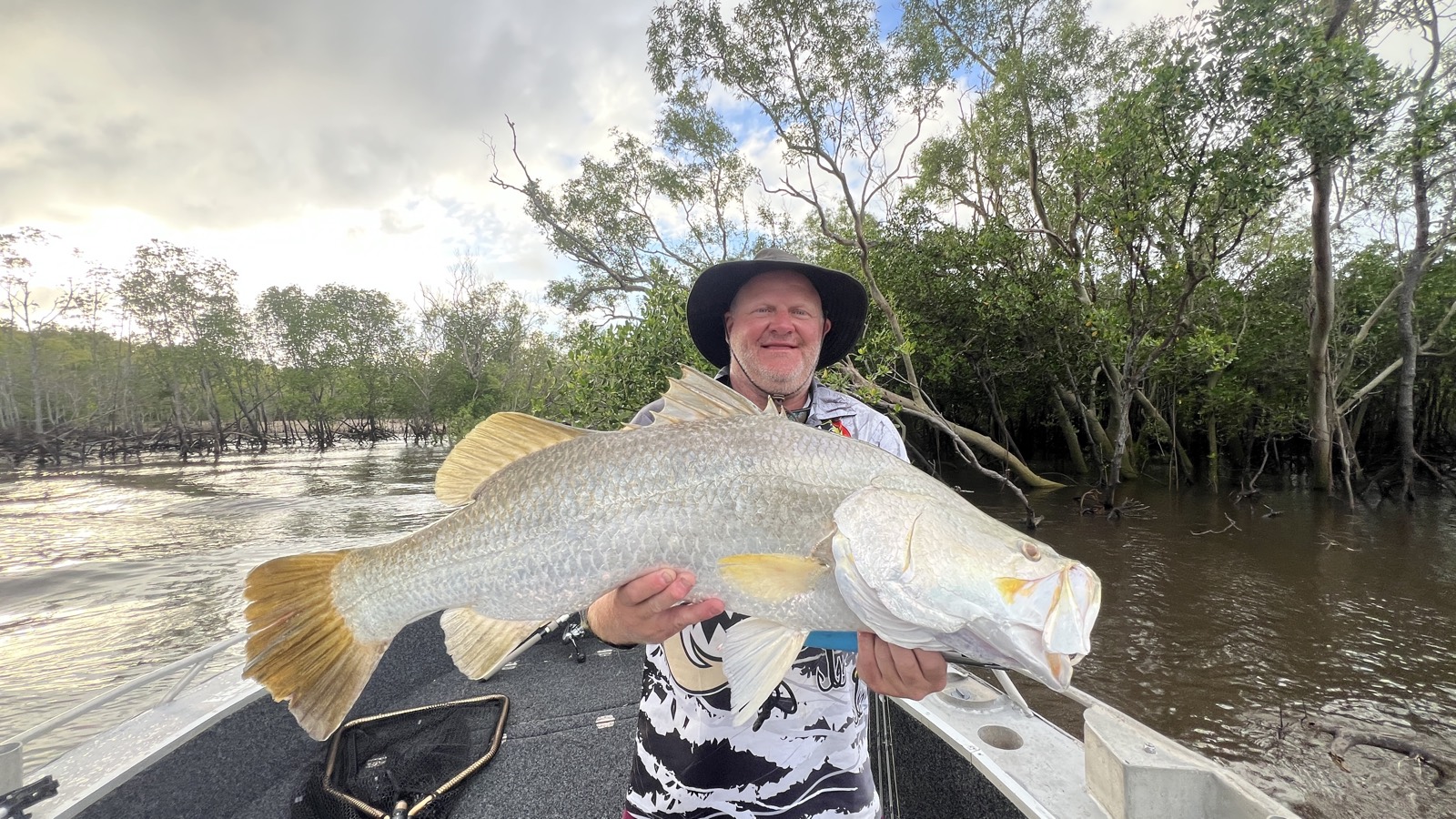 Angler holding a big golden barramundi in a Top End mangrove creek on a Cape Adieu barra charter