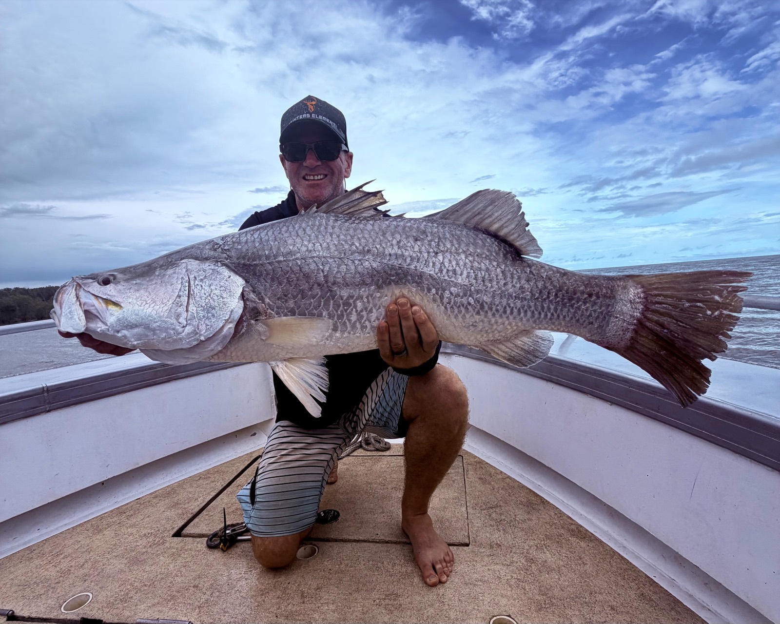 Angler with a big silver barramundi in open coastal water on a Top End barra charter