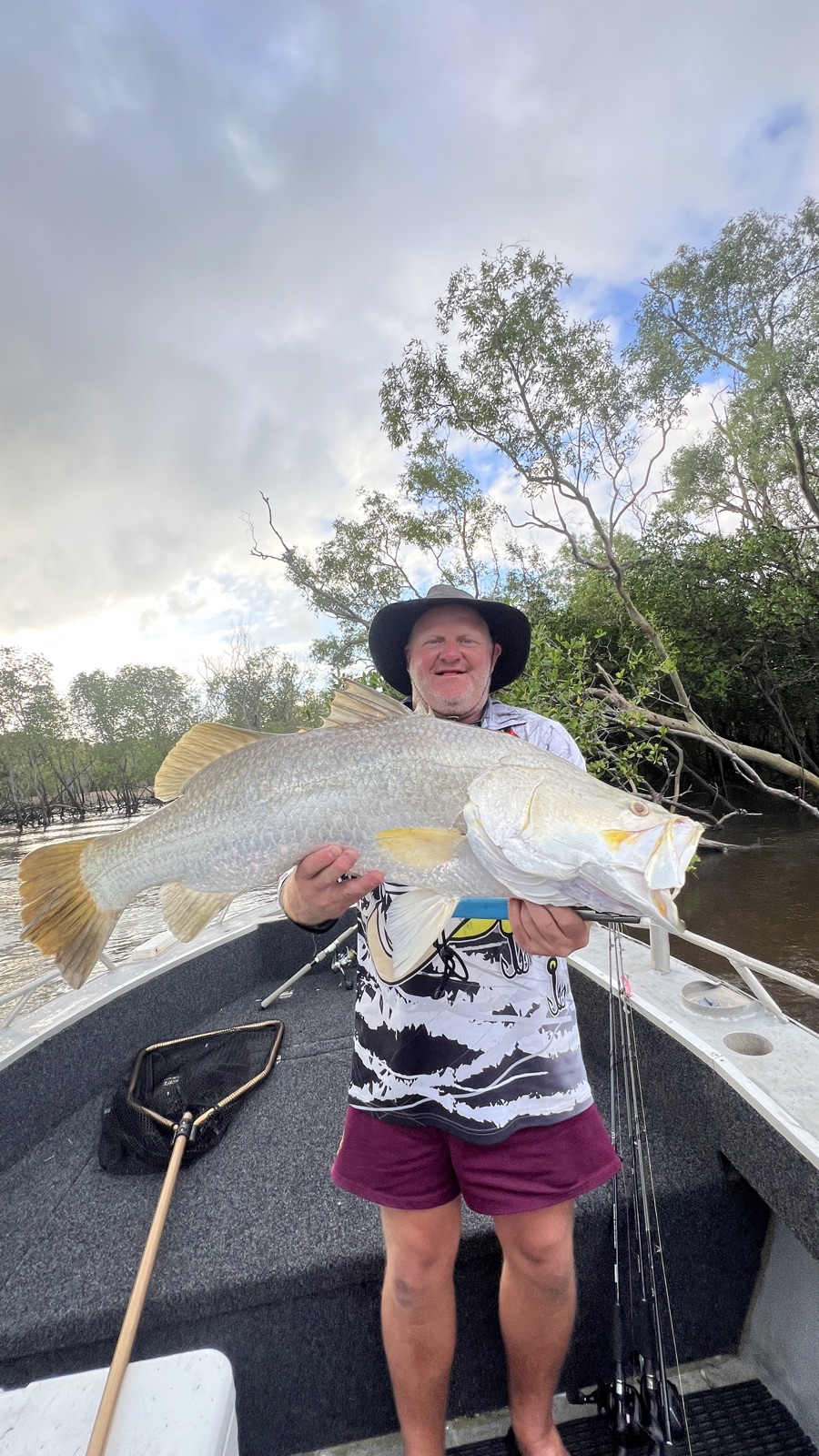 Angler holding a barramundi on a Top End creek fishing charter
