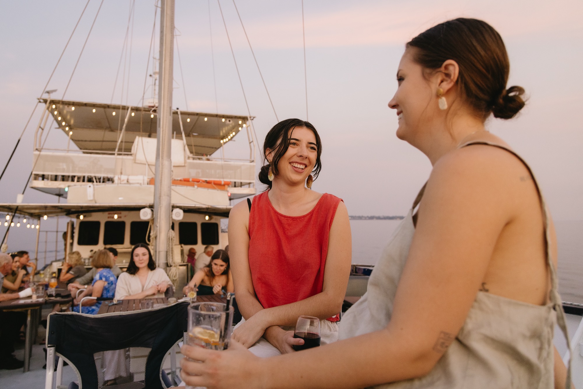 Friends laughing over drinks at sunset on a private Cape Adieu charter