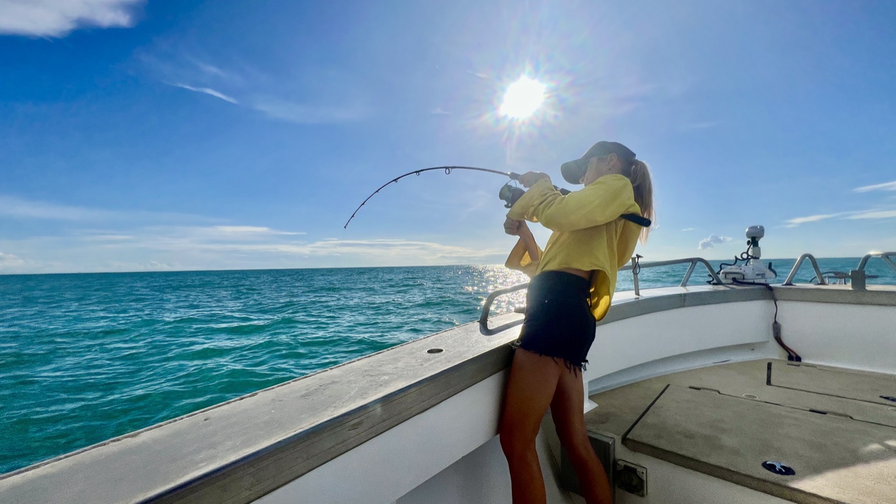 Angler hooked up and fighting a fish on the bow during a Darwin Harbour charter